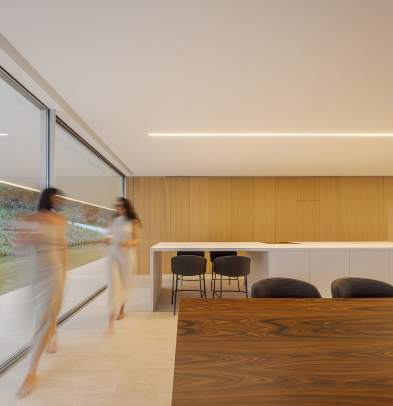 Minimalistyczny dom otoczony wzg&oacute;rzami i lasami. Na dachu – ogromna tafla wody.